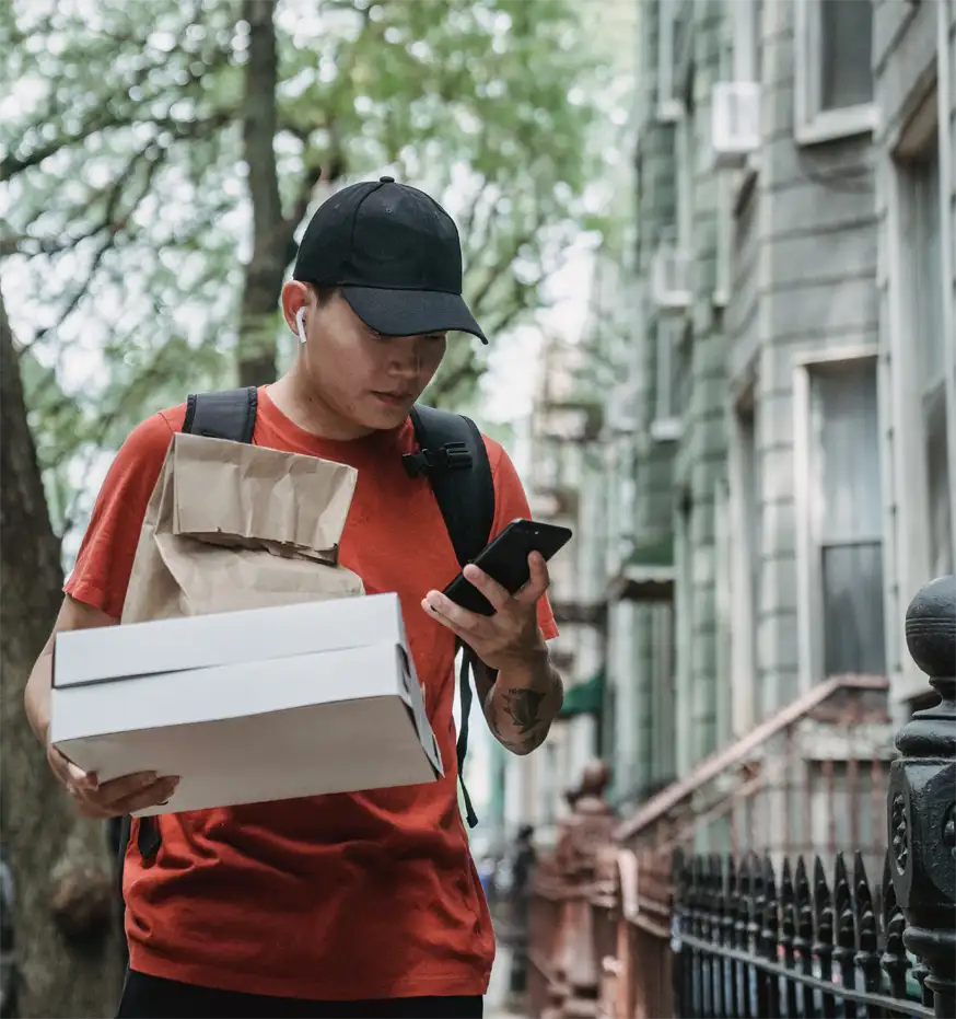 Man håller mobiltelefon och lådor på gatan